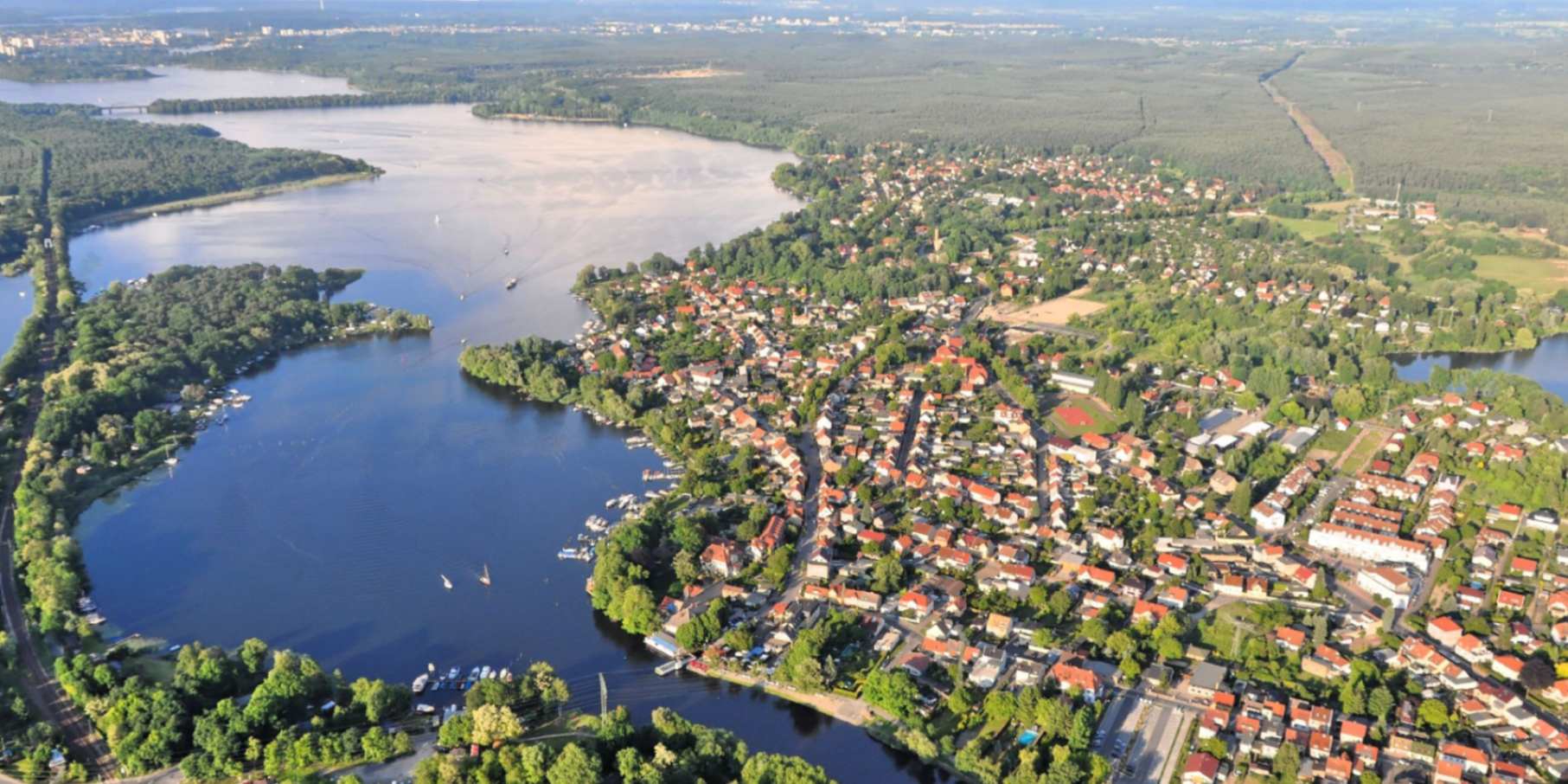 Panoramatický letecký snímek jezera Templiner See a sousedního městečka uprostřed letní krajiny