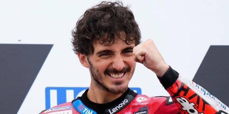 Francesco Bagnaia v červené závodní kombinéze stáje Ducati, který slaví vítězství