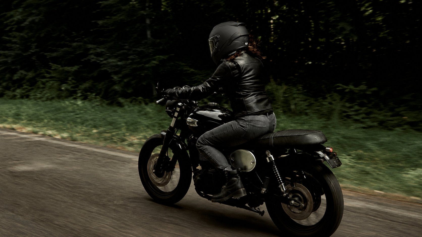 Motorkářka v černé kožené moto bundě při jízdě na motorce