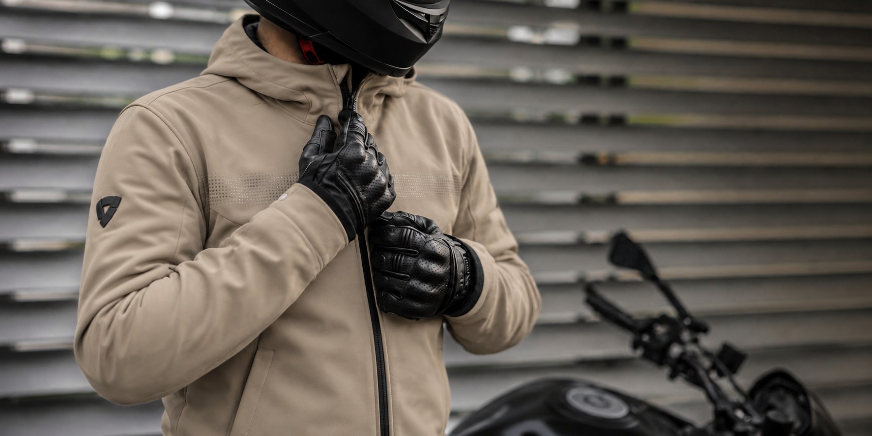 Motorkár v béžovej moto mikine a rukaviciach