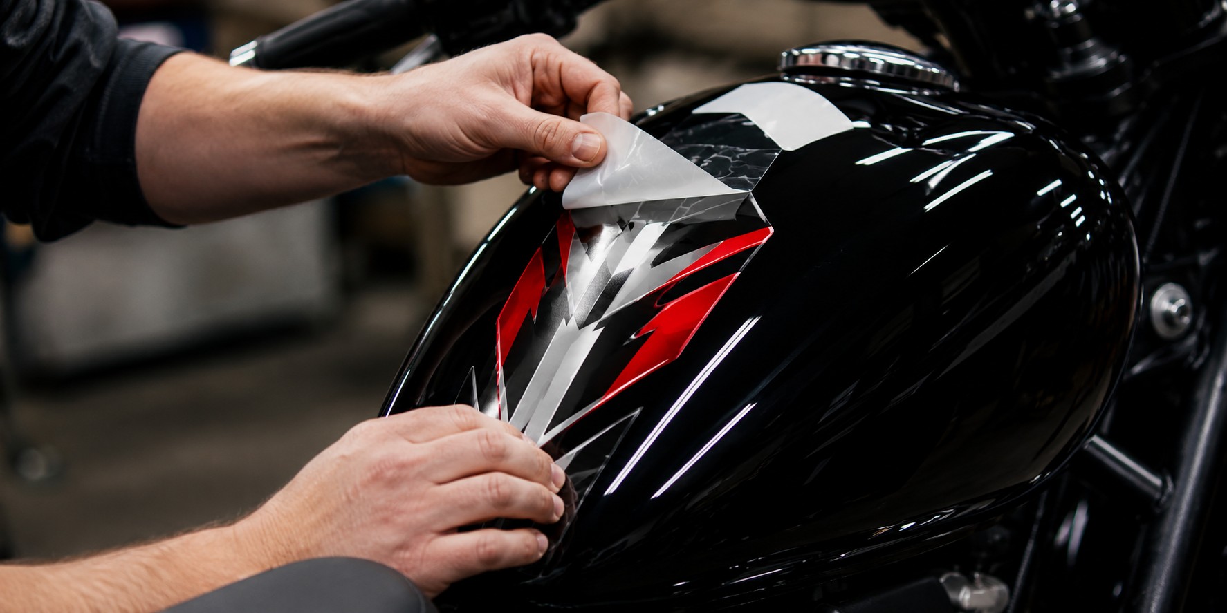Aplikácia dizajnového červeno-bieleho polepu na lesklú palivovú nádrž motocykla
