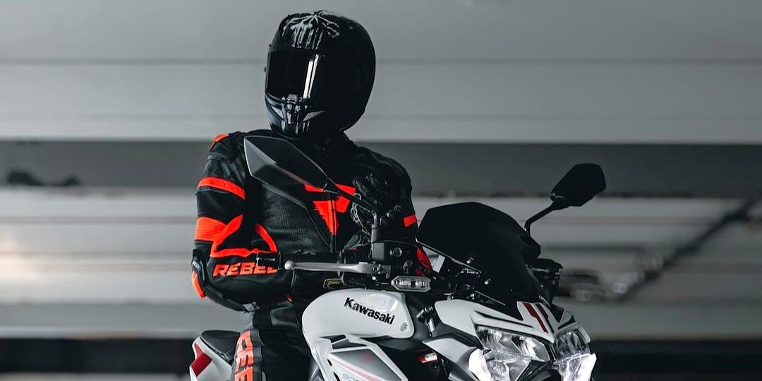 Motorkár v červeno-čiernej koženej moto bunde Rebelhorn na motocykli Kawasaki