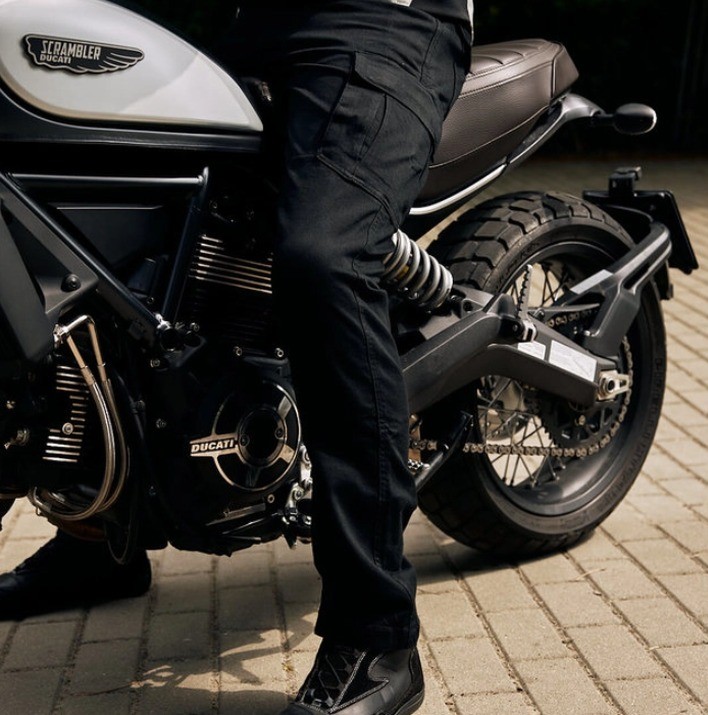 detail na motorkáře v textilních kalhotách na motorku